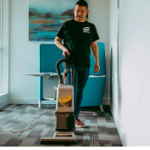 Professional cleaner dusting a shelf in a bright, tidy living room