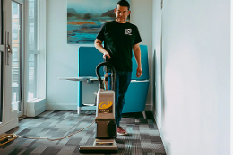 Professional cleaner dusting a shelf in a bright, tidy living room